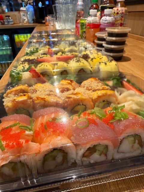 Assorted sushi rolls on wooden counter including rolls with salmon roe
