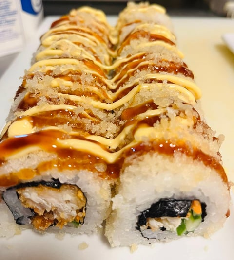 Sushi rolls topped with eel sauce and sesame seeds featuring shrimp tempura