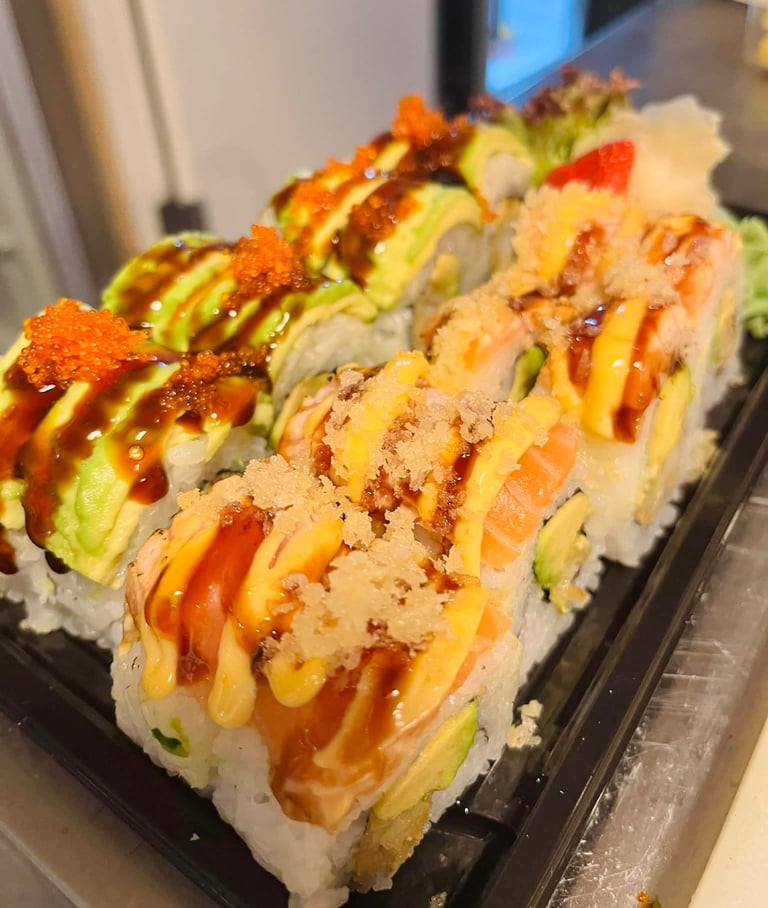 Close-up of sushi rolls topped with salmon, avocado, and roe
