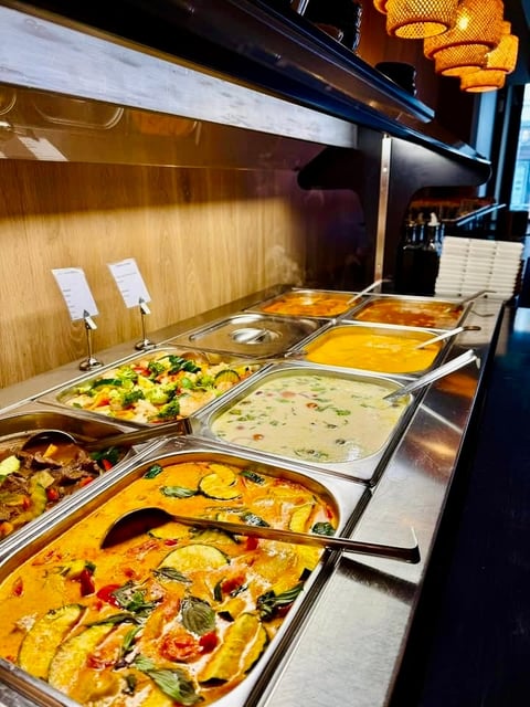 Buffet line with multiple stainless steel containers of colorful prepared dishes