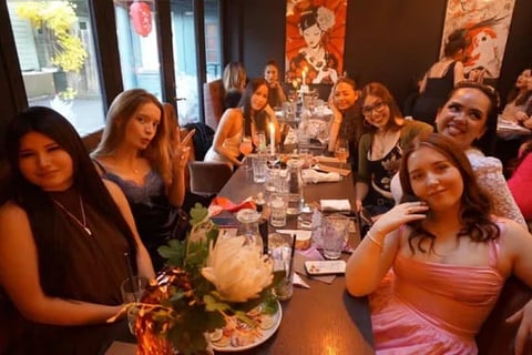 Group of women dining together at a long table during an indoor dinner party or celebration event