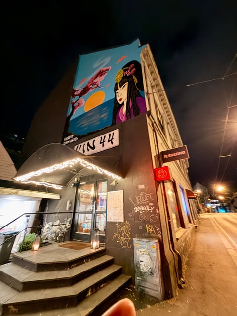 Night view of a vintage cinema with colorful art deco murals on the roof and illuminated marquee