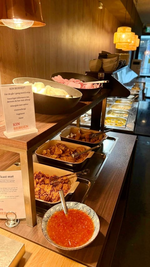 Buffet display with assorted dishes in black trays including meats and vegetables